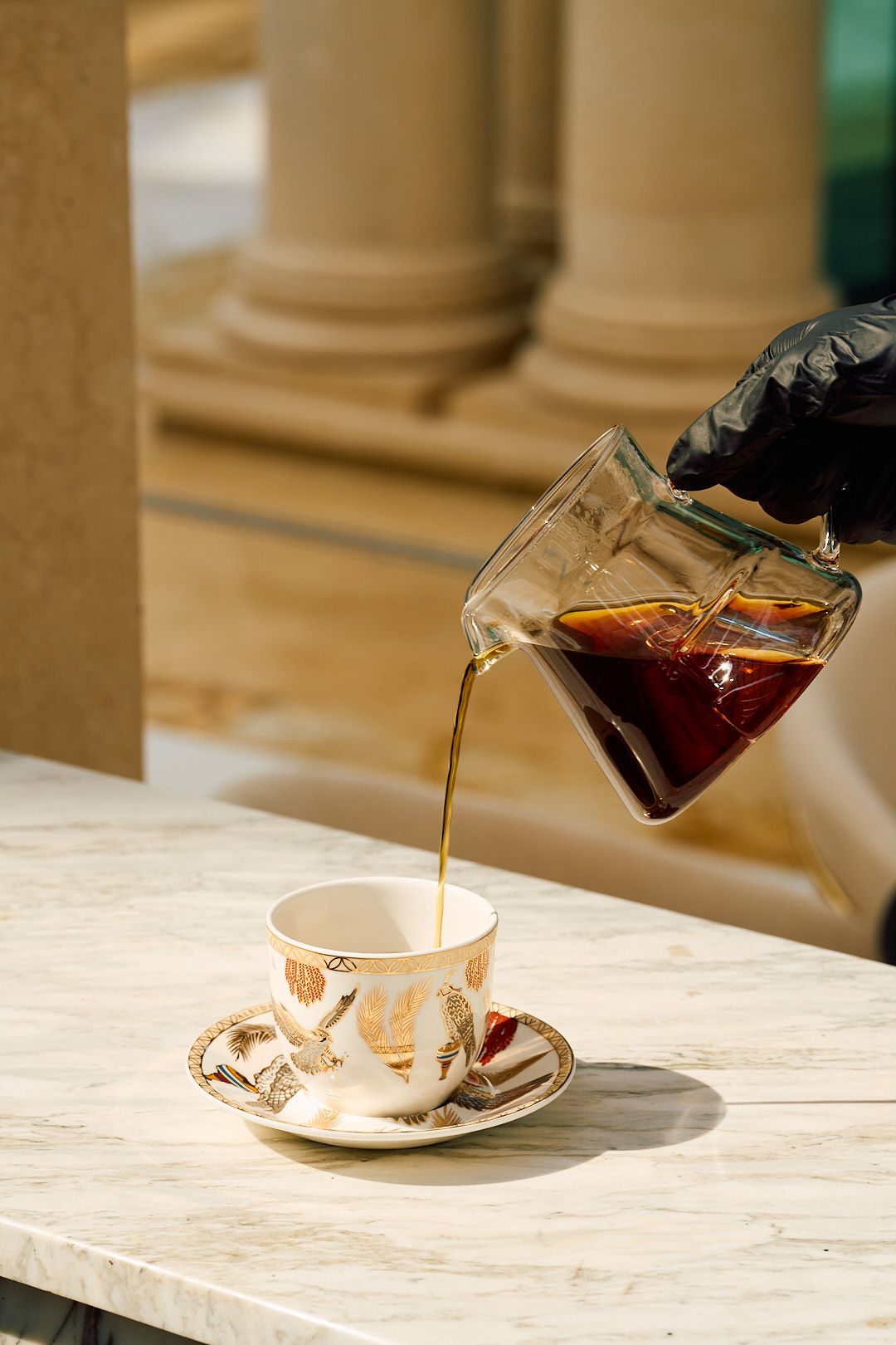 Pour-over coffee being served on marble among pale stone columns
